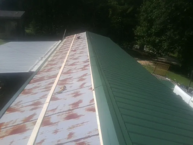 Old rusted panels beside newly installed green metal roofing — Wind Damage Roof Repair by Roofing Brothers in Blackshear