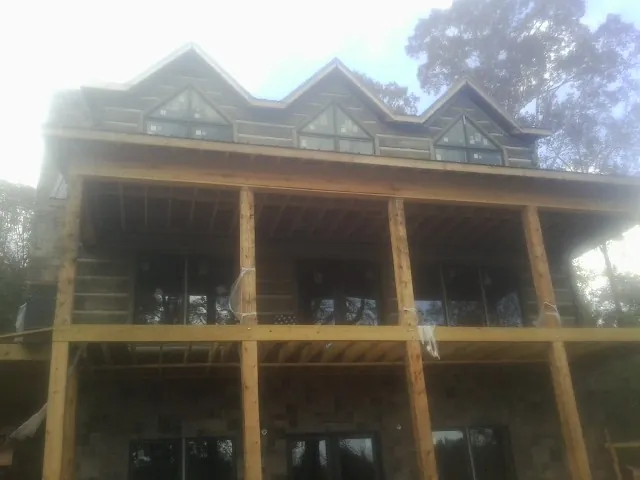 Dormers and porch framing on a large log home under construction — Roof Coating work by our crew in Blackshear